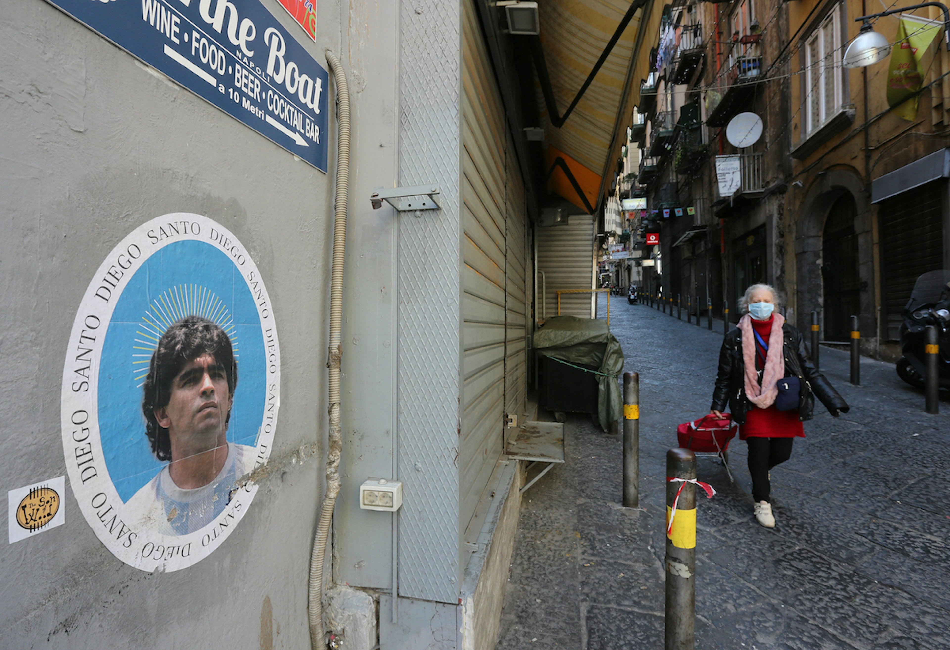 A woman wearing protective mask passes next to a closed shop