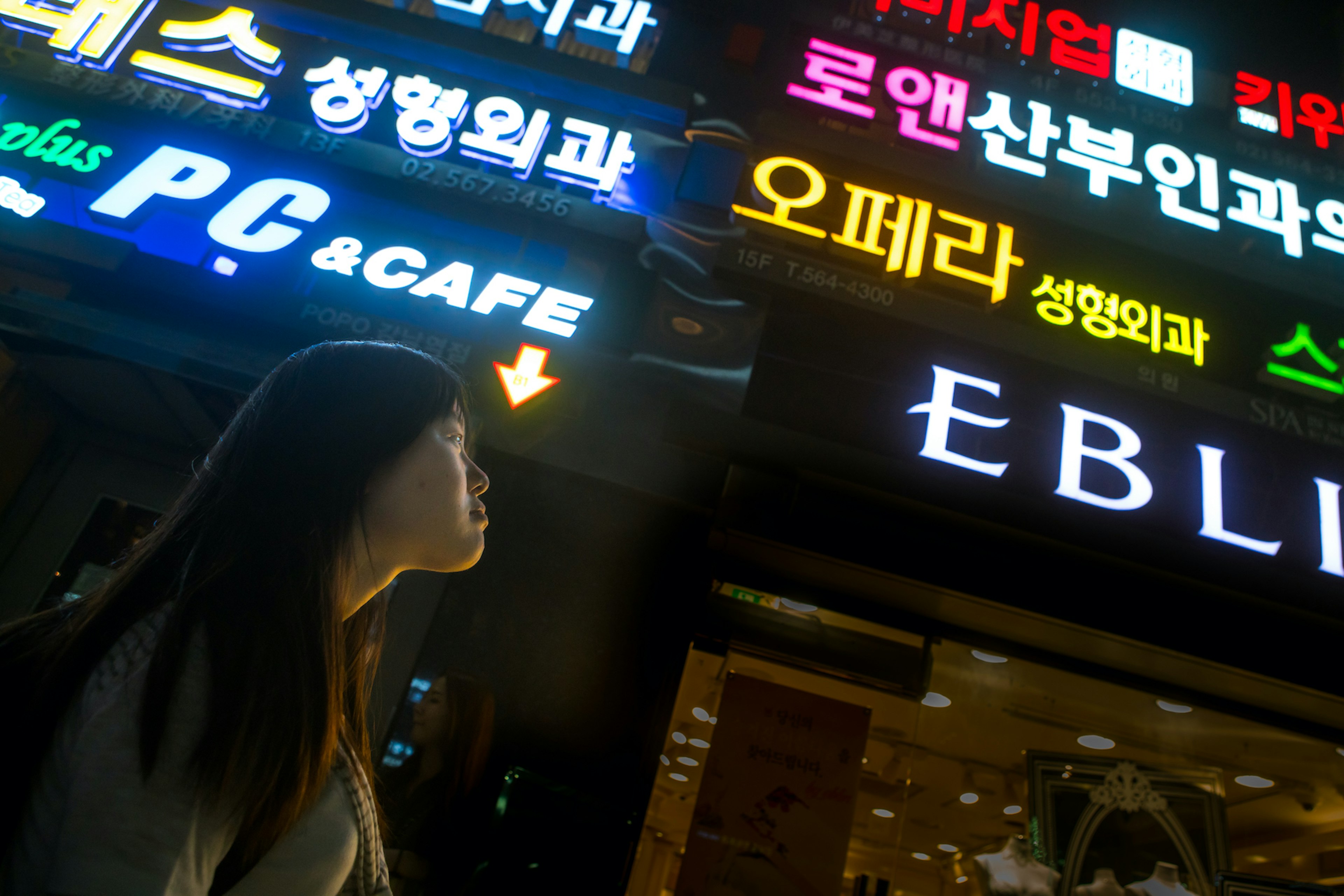 North korean teen defector in front of neon lights in the street, National capital area, Seoul, South korea